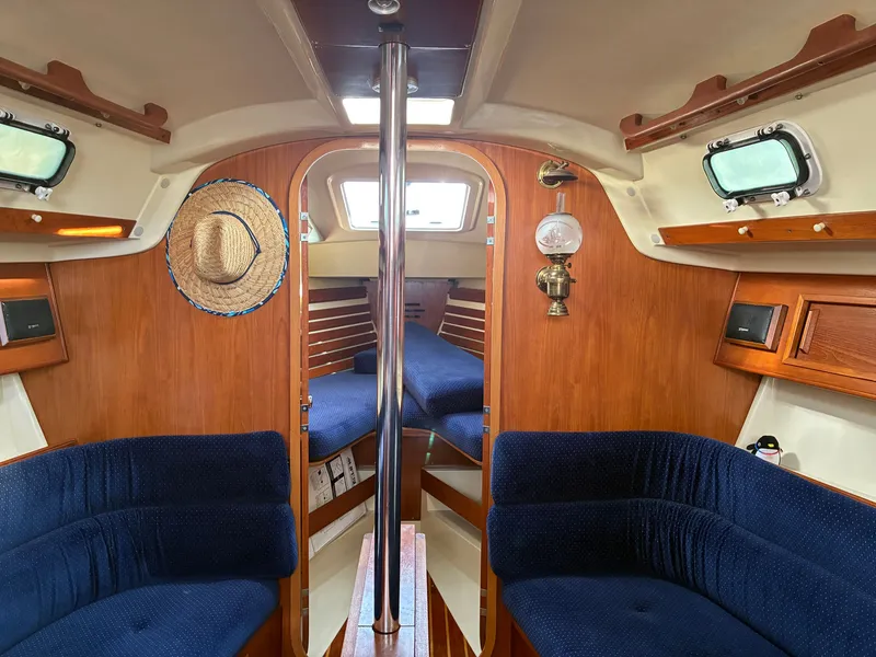Slide: The Image of The interior of a 1988 Pearson 33-2 features a cozy cabin with blue upholstery and wooden walls. - 23
