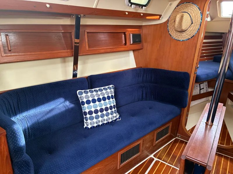 Slide: The Image of The interior of a 1988 Pearson 33-2 features a blue couch with a patterned pillow. - 32
