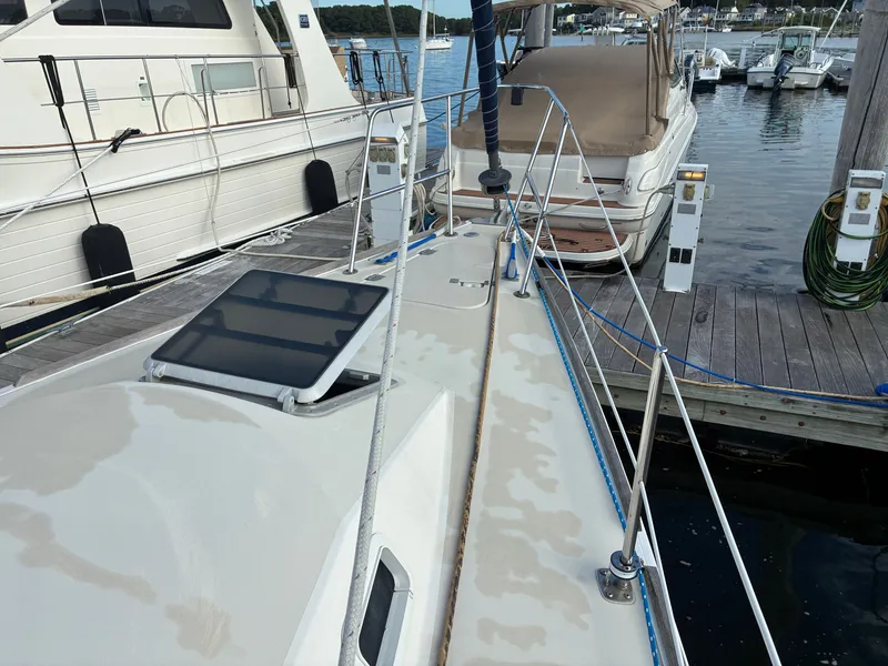 Slide: The Image of A 1988 Pearson 33-2 sailboat docked. It features a clean deck and is surrounded by other boats. - 5