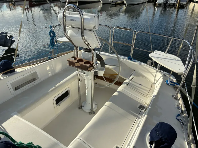 Slide: The Image of The cockpit of a 1988 Pearson 33-2 with a steering wheel and seating, docked at a marina. - 13