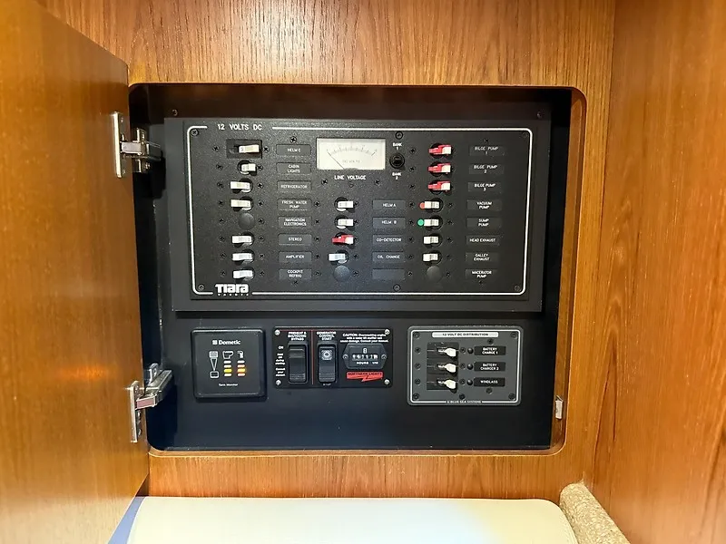 Slide: The Image of Electrical control panel in a 2013 Tiara Yachts 3600 Open, set within a wooden cabinet. - 37
