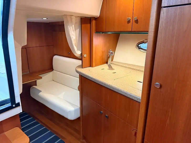 Slide: The Image of Interior of a 2013 Tiara Yachts 3600 Open with wood cabinetry and a white sofa. - 28