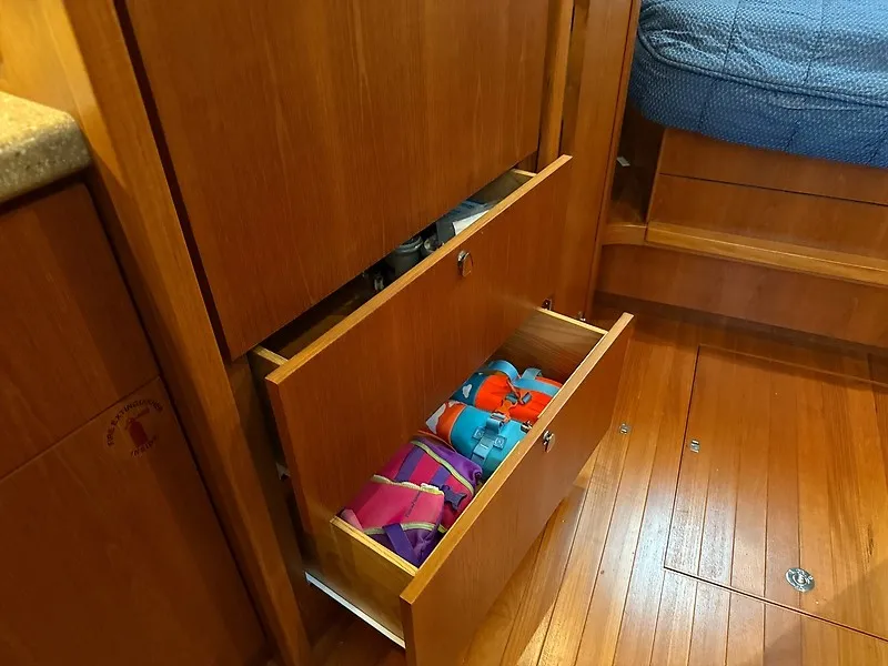 Slide: The Image of A wooden cabinet with two open drawers containing colorful life jackets on a boat. - 31