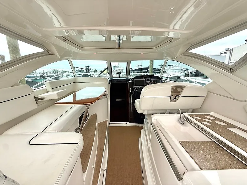 Slide: The Image of Interior of a 2013 Tiara Yachts 3600 Open with sleek white seating and a wooden table. - 7