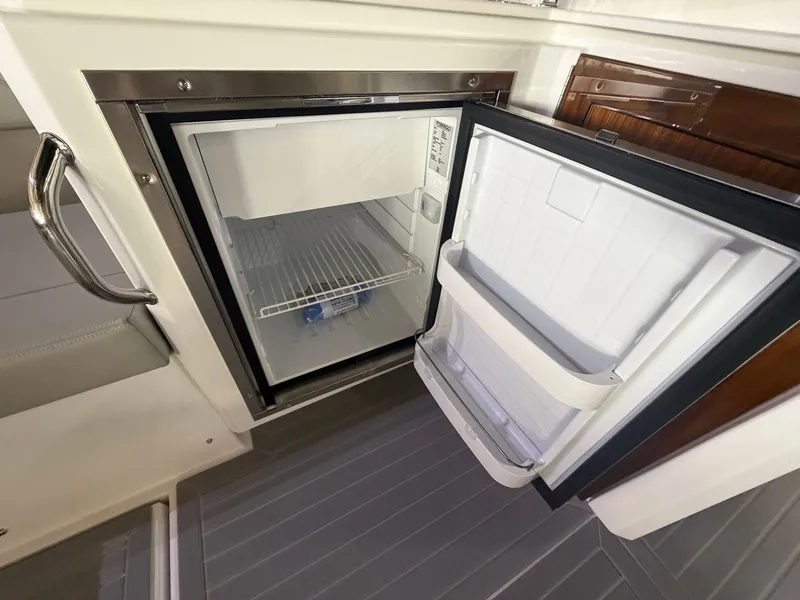 Slide: The Image of An open fridge on a yacht with a gray floor and wood paneling. - 24