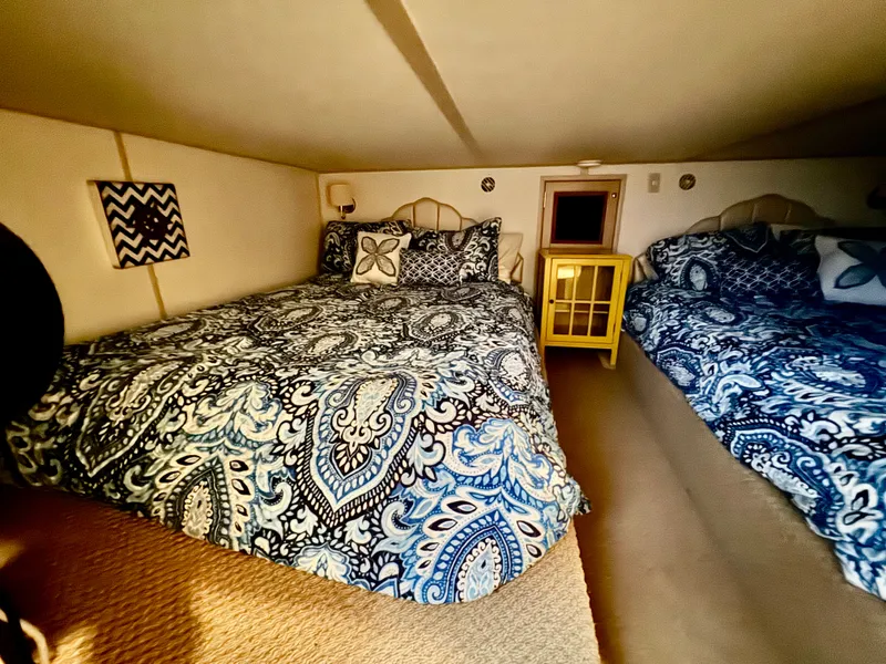 Slide: The Image of Acogedor dormitorio con dos camas grandes, decorado con colchas de paisley azul y una mesita amarilla. - 30