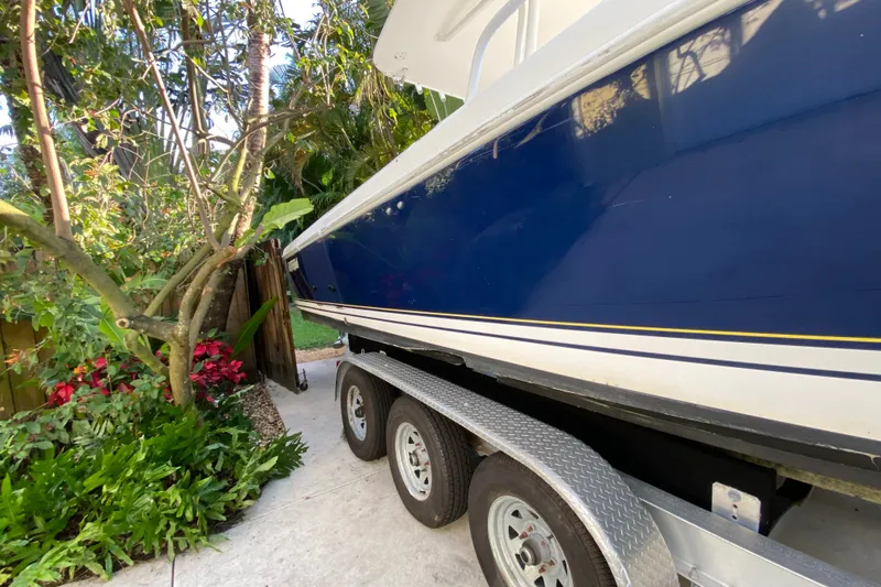 Slide: The Image of 2007 Intrepid 323 Cuddy boat on trailer, surrounded by lush greenery. - 23