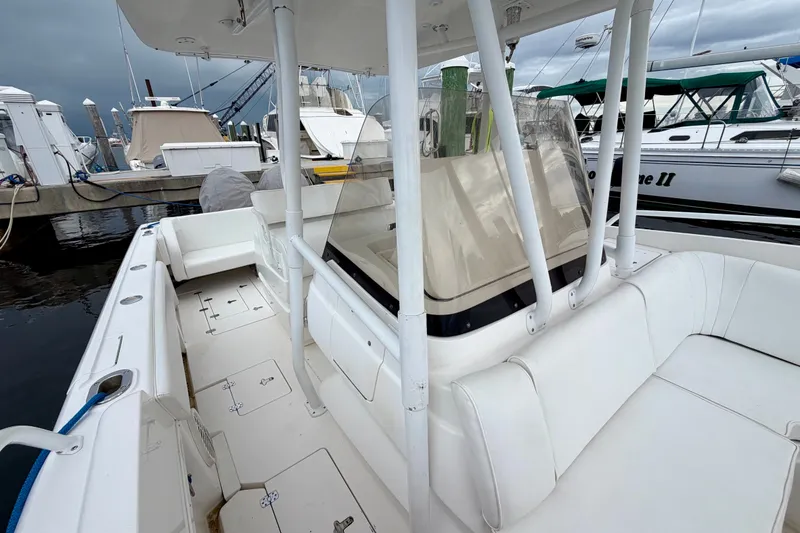 Slide: The Image of 2007 Intrepid 327 Cuddy boat interior with white seating at a marina dock. - 9