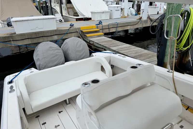Slide: The Image of 2007 Intrepid 327 Cuddy boat interior at marina dock, featuring seating and covered engines. - 10