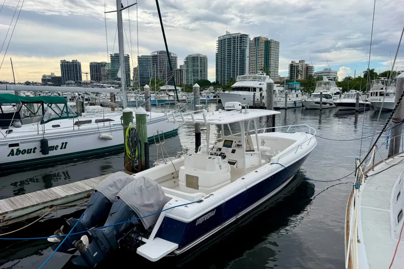 Slide: The Image of 2007 Intrepid 327 Cuddy boat docked in a marina with city skyline background. - 1