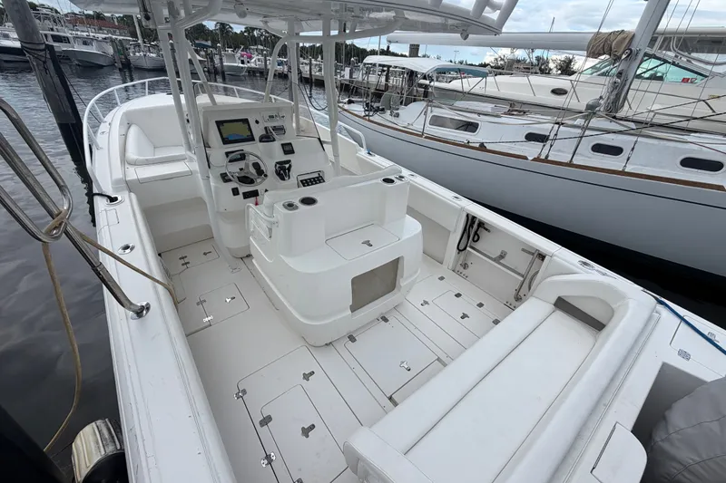 Slide: The Image of 2007 Intrepid 327 Cuddy boat interior with helm, seating, and docked sailboats in background. - 11