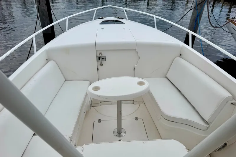 Slide: The Image of 2007 Intrepid 327 Cuddy boat interior with white seating and table, docked by the water. - 5