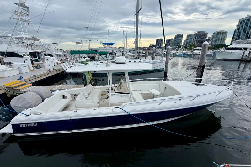Slide: The Image of 2007 Intrepid 327 Cuddy boat docked at marina with city skyline in background. - 0