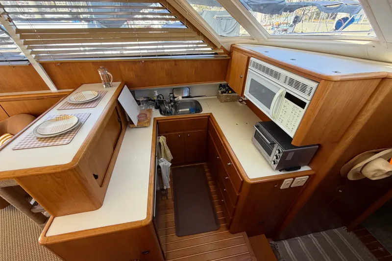 Slide: The Image of Interior of 2000 Tiara Yachts 4300 Convertible, featuring a compact kitchen with wooden cabinetry. - 29