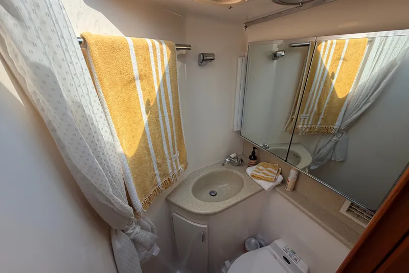 Slide: The Image of Compact bathroom in 2000 Tiara Yachts 4300 Convertible, featuring sink, mirror, and yellow towel. - 31