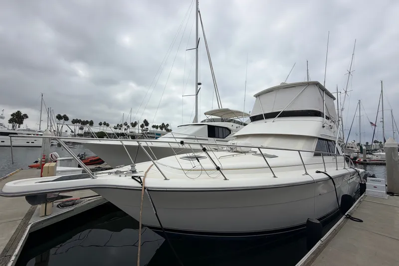 Slide: The Image of 2000 Tiara Yachts 4300 Convertible docked at marina under cloudy skies. - 2