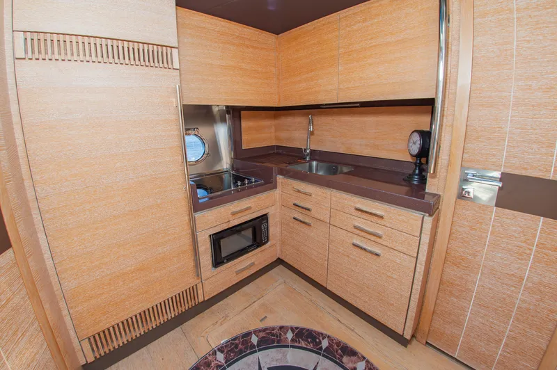 Slide: The Image of The 2008 Azimut 47 kitchen features wooden cabinets, a stove, sink, and microwave. - 23