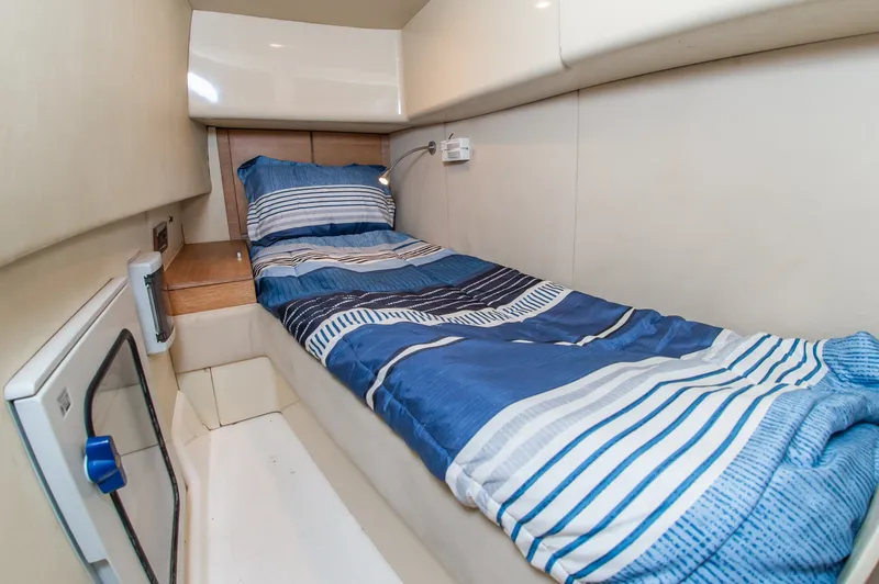 Slide: The Image of A narrow cabin with a single bed covered in blue-striped bedding. - 35