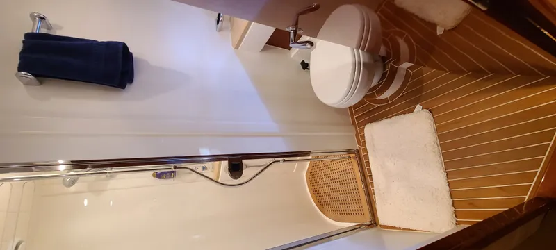 Slide: The Image of The image shows a boat bathroom with wooden flooring, a shower, and a toilet. - 20