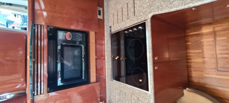 Slide: The Image of The yacht's kitchen features wooden cabinets, a built-in oven, and a cooktop. - 17