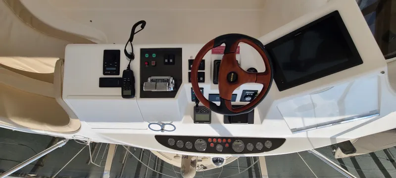 Slide: The Image of The image shows the helm of a 2006 Viking Princess 61 Flybridge with a wooden steering wheel and modern instruments. - 11