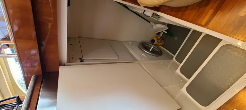 Slide: The Image of The laundry area on the 2006 Viking Princess 61 Flybridge features a washing machine and dryer. - 18