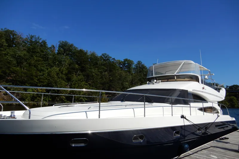 Slide: The Image of 2008 Viking Sport Cruisers 61 Motor Yacht docked by lush green trees. - 3