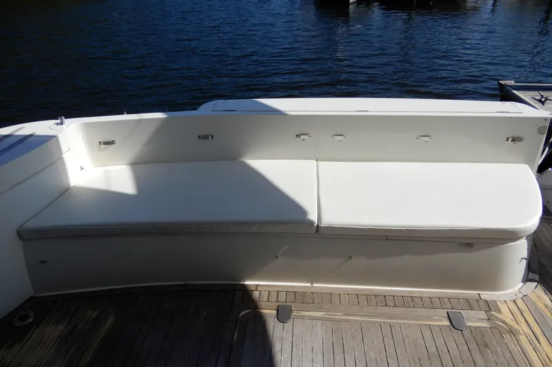 Slide: The Image of 2008 Viking Sport Cruisers 61 Motor Yacht seating area with white cushions and wooden deck. - 11