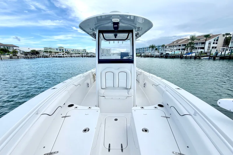 Slide: The Image of 2017 Sea Hunt Gamefish 27 boat on calm water, with coastal buildings in the background. - 24