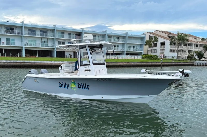 Slide: The Image of 2017 Sea Hunt Gamefish 27 boat named "Dilly Dilly" on water near waterfront buildings. - 2