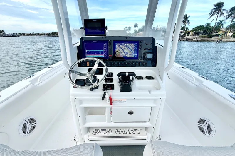 Slide: The Image of 2017 Sea Hunt Gamefish 27 boat dashboard with navigation screens and steering wheel. - 18