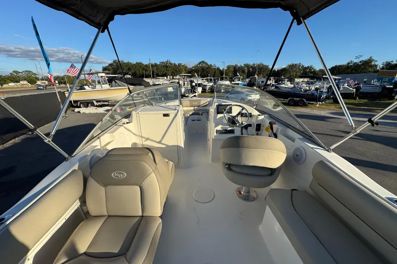 Slide: The Image of 2021 Key West 203 DFS boat interior with seating and steering wheel, parked outdoors. - 18