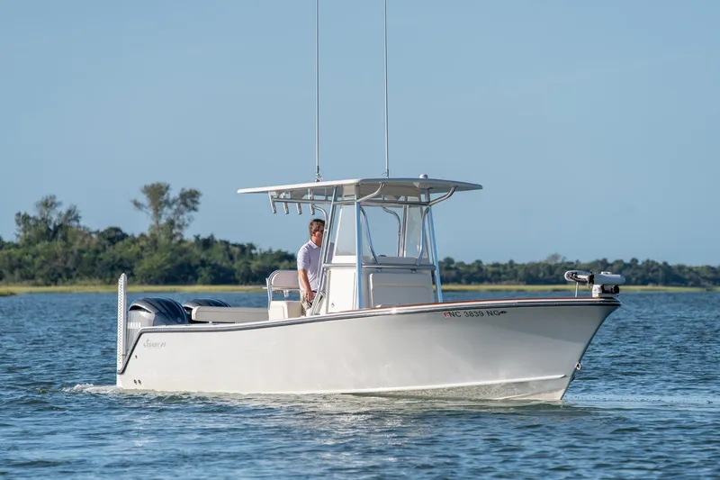 Slide: The Image of 2023 Stuart 27 Center Console boat cruising on a calm lake with a clear sky. - 5