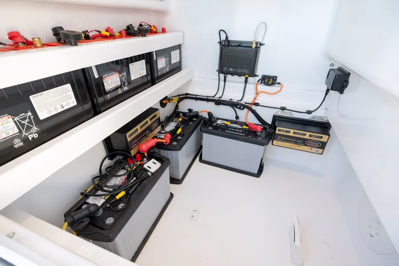 Slide: The Image of Battery compartment of 2023 Stuart 27 Center Console boat, showcasing multiple batteries and wiring. - 17