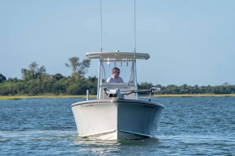 Slide: The Image of 2023 Stuart 27 Center Console boat cruising on a calm lake with trees in the background. - 3