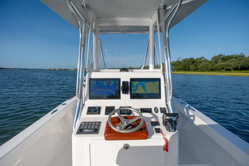Slide: The Image of 2023 Stuart 27 Center Console boat dashboard with dual navigation screens on calm water. - 11