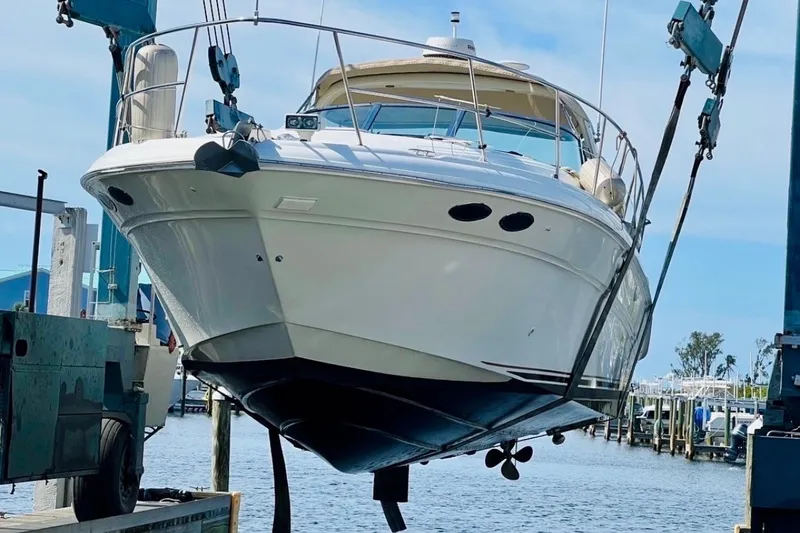 Slide: The Image of 2000 Sea Ray 410 Sundancer yacht lifted at marina, showcasing sleek design and craftsmanship. - 68