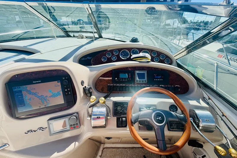 Slide: The Image of Cockpit of 2000 Sea Ray 410 Sundancer with navigation screens and wooden steering wheel. - 42