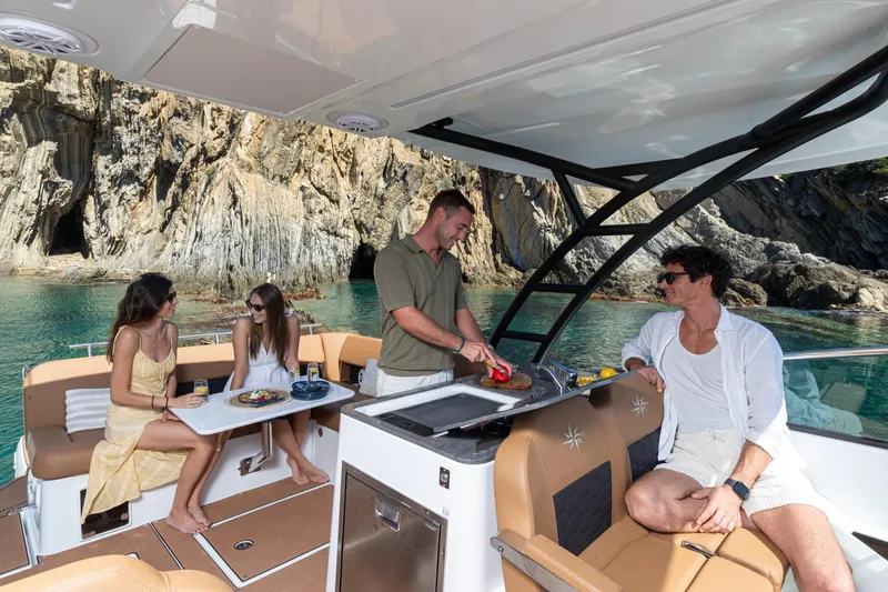 Slide: The Image of People enjoying a meal on a 2027 Jeanneau TH33 boat near rocky cliffs. - 8
