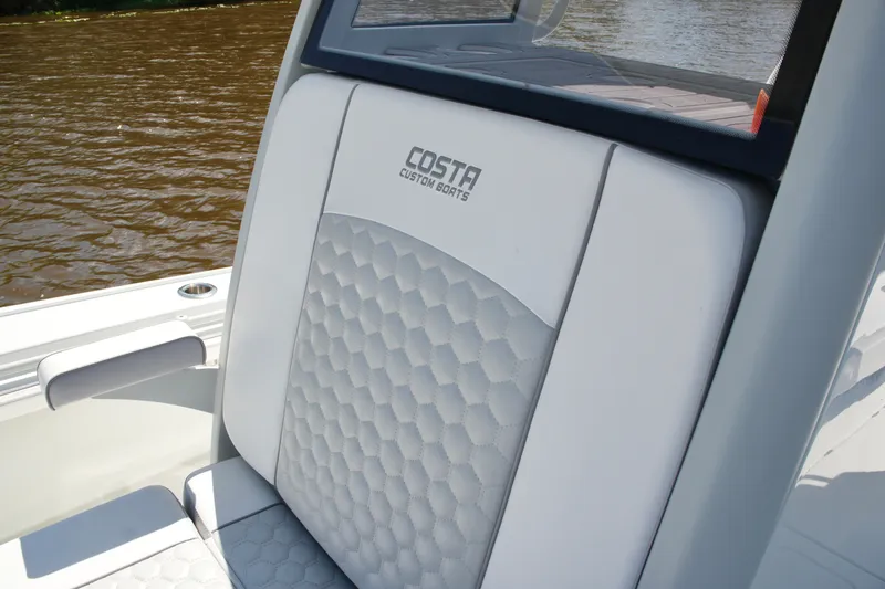 Slide: The Image of 2024 Costa Custom Boats 264HC seat with hexagonal pattern, on a river. - 54
