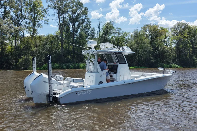 Slide: The Image of 2024 Costa Custom Boats 264HC on a scenic river with lush trees. - 8