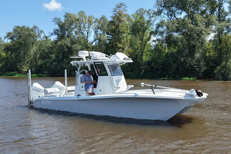 Slide: The Image of 2024 Costa Custom Boats 264HC on a scenic river with lush trees in the background. - 11