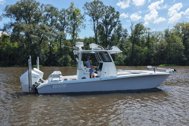 Slide: The Image of 2024 Costa Custom Boats 264HC on a scenic river with lush trees. - 9