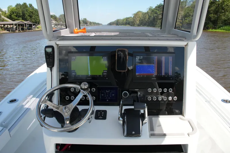 Slide: The Image of 2024 Costa Custom Boats 264HC helm with advanced navigation displays on a serene river. - 31