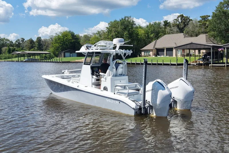 Slide: The Image of 2024 Costa Custom Boats 264HC on a serene lake with lush greenery. - 17
