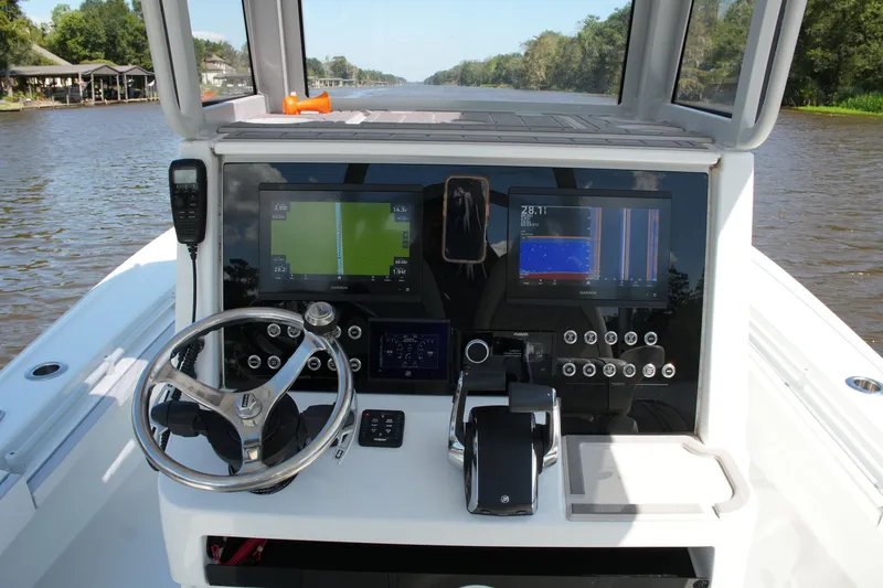 Slide: The Image of 2024 Costa Custom Boats 264HC helm with advanced navigation displays on a scenic river. - 57