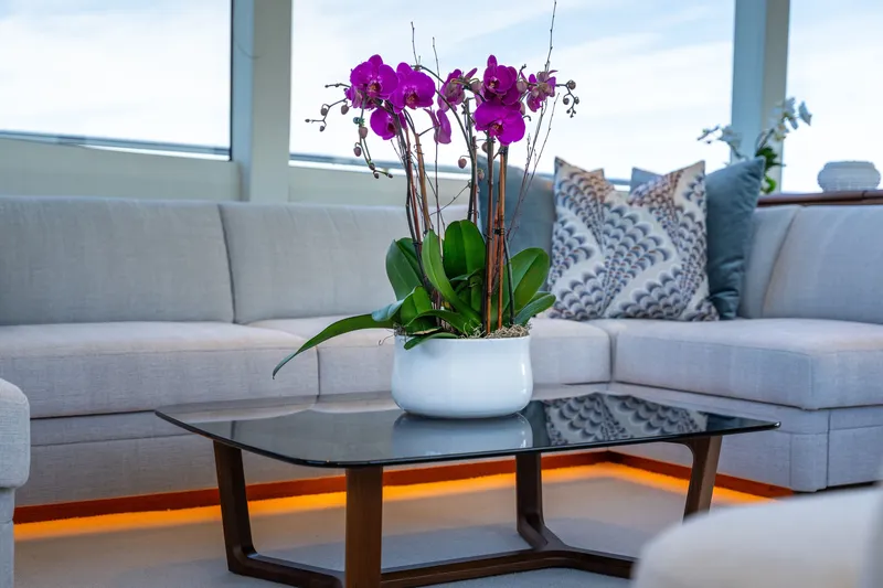 Slide: The Image of A stylish yacht living area with a modern glass table and an orchid centerpiece. - 20