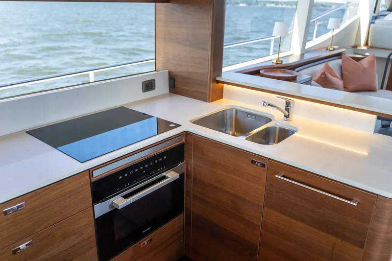 Slide: The Image of Modern yacht kitchen with wooden cabinets, double sink, and cooktop, overlooking the water. - 12
