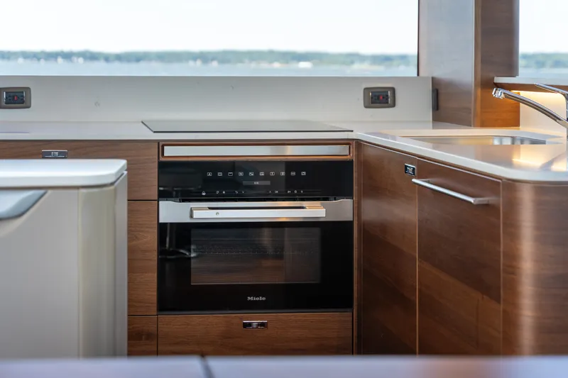 Slide: The Image of Modern yacht kitchen with wood paneling and Miele oven, overlooking the water. - 13