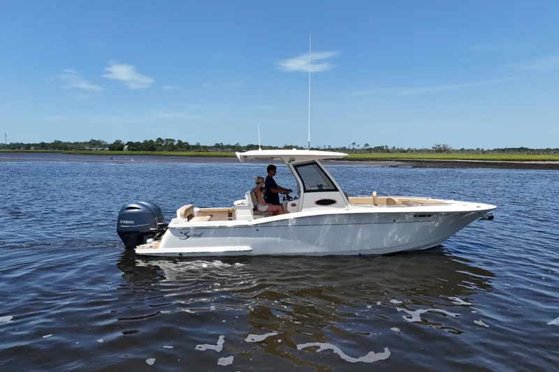 Slide: The Image of 2021 Scout 277 LXF boat cruising on calm waters under a clear blue sky. - 19